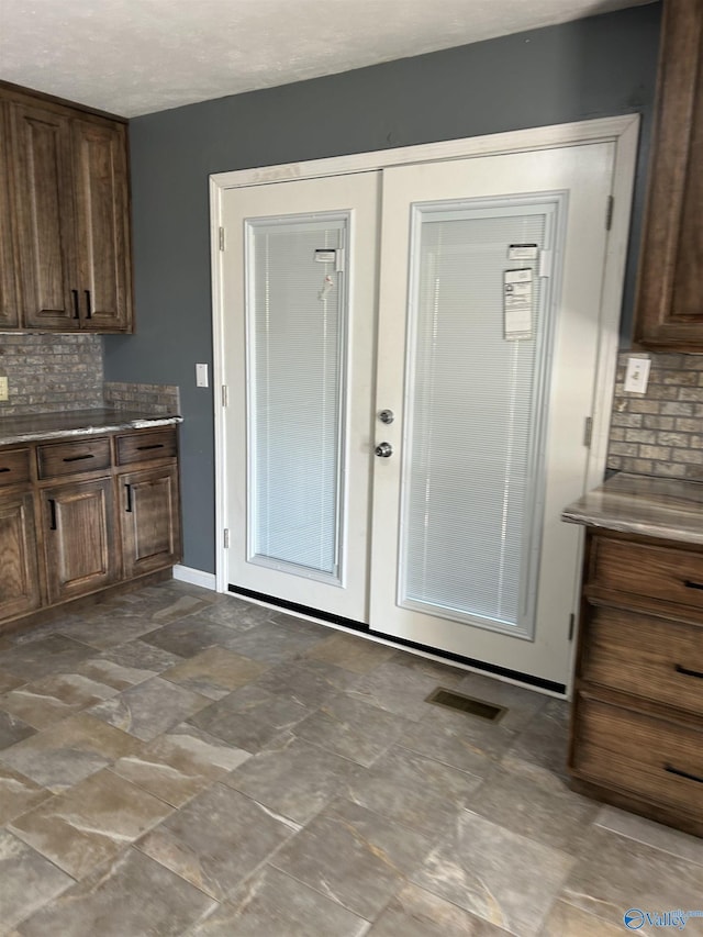 interior space with french doors, backsplash, visible vents, dark brown cabinets, and baseboards