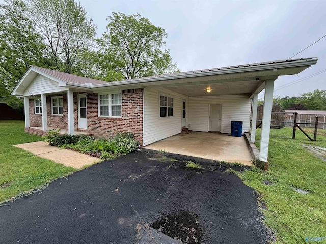 single story home with a front yard, brick siding, fence, aphalt driveway, and an attached carport