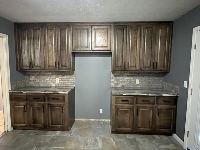 kitchen featuring baseboards, decorative backsplash, and dark brown cabinetry