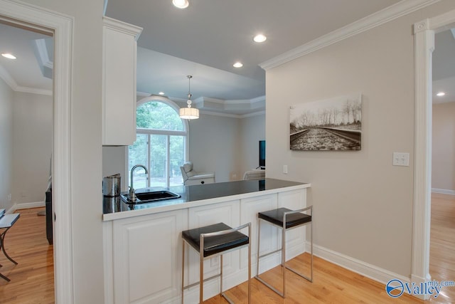 kitchen featuring light wood-type flooring, a sink, white cabinets, and crown molding