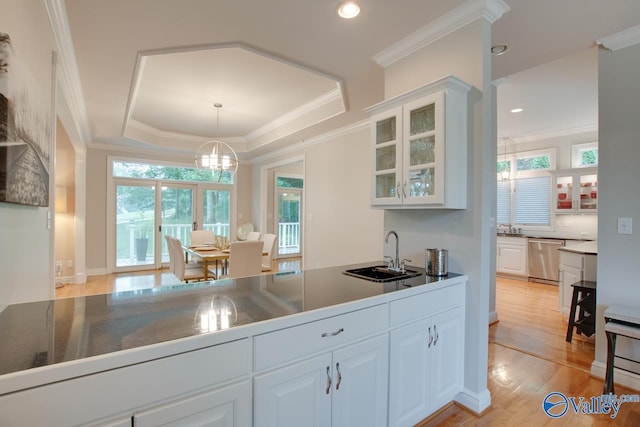 kitchen with a sink, ornamental molding, dishwasher, a raised ceiling, and glass insert cabinets