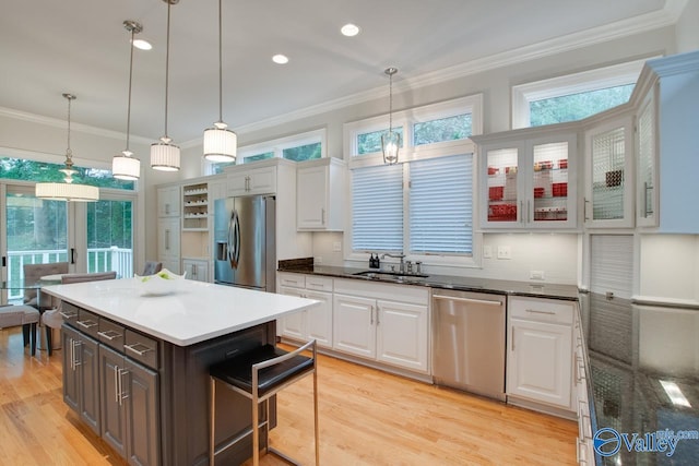 kitchen featuring appliances with stainless steel finishes, white cabinetry, a sink, and ornamental molding