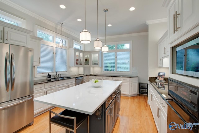 kitchen with crown molding, white cabinetry, a sink, light wood-type flooring, and black appliances