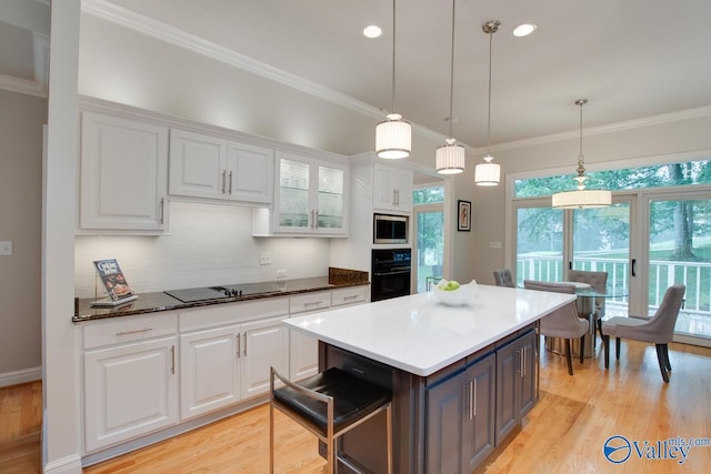 kitchen featuring white cabinets, crown molding, and black appliances