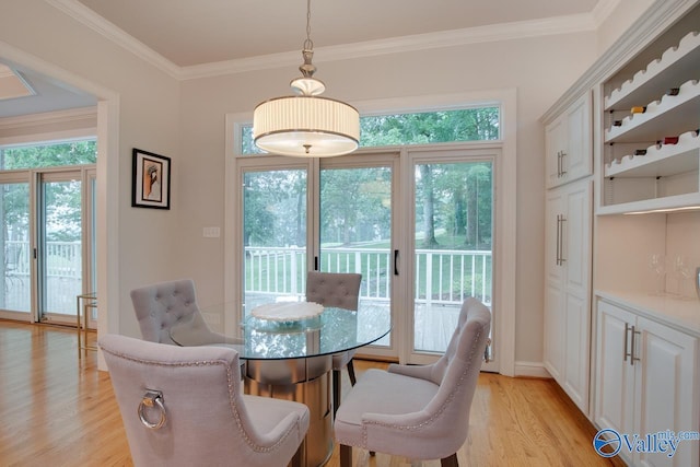 dining area featuring light wood-style floors, baseboards, and crown molding