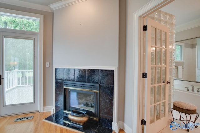 interior space featuring visible vents, wood finished floors, crown molding, and a tile fireplace