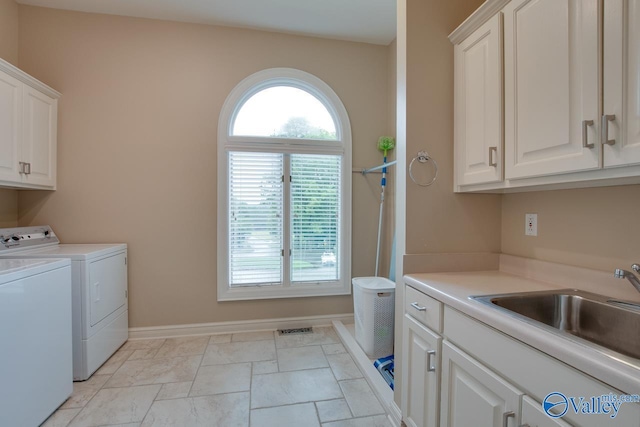 laundry room with cabinet space, baseboards, visible vents, washer and dryer, and a sink