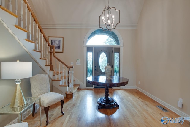 foyer with baseboards, visible vents, wood finished floors, stairs, and a notable chandelier