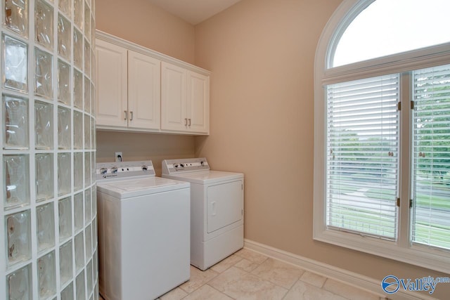 laundry area with baseboards, cabinet space, stone finish floor, and washing machine and clothes dryer