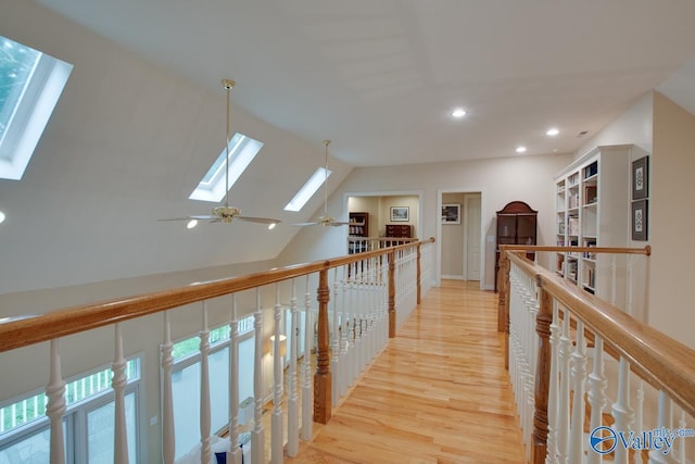 corridor featuring lofted ceiling with skylight, an upstairs landing, light wood-style flooring, and recessed lighting