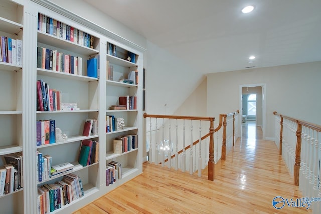 hall featuring wood finished floors, an upstairs landing, and recessed lighting