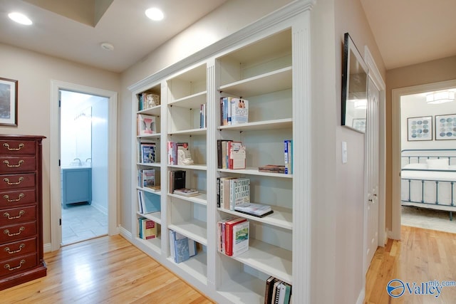 hall featuring baseboards, light wood-style flooring, and recessed lighting