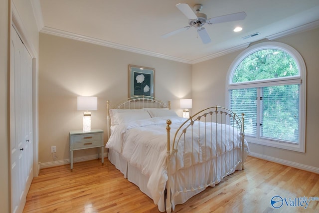 bedroom with crown molding, a closet, visible vents, light wood-style floors, and baseboards