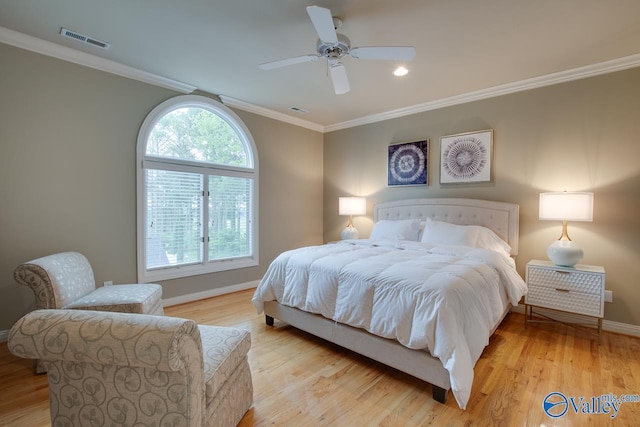 bedroom with baseboards, light wood-style floors, visible vents, and crown molding