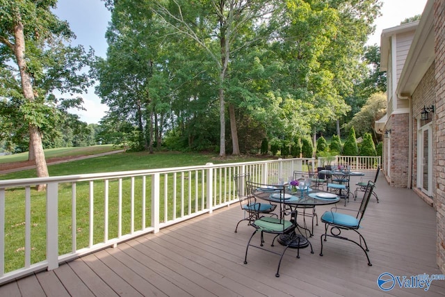 deck featuring outdoor dining area and a lawn