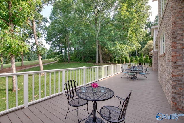 wooden terrace with a yard and outdoor dining area