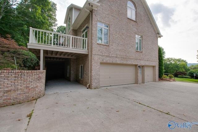 view of side of property with a garage, driveway, and brick siding