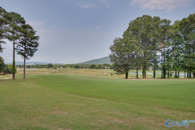 surrounding community with view of golf course, a lawn, and a mountain view