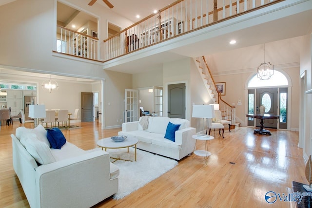 living area featuring baseboards, wood finished floors, stairs, french doors, and a chandelier