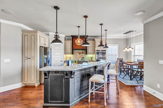 kitchen featuring cream cabinets, dark wood-style flooring, appliances with stainless steel finishes, backsplash, and light stone countertops