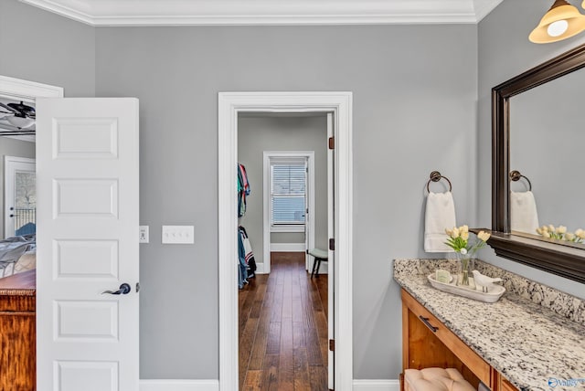 bathroom featuring vanity, baseboards, crown molding, and wood finished floors