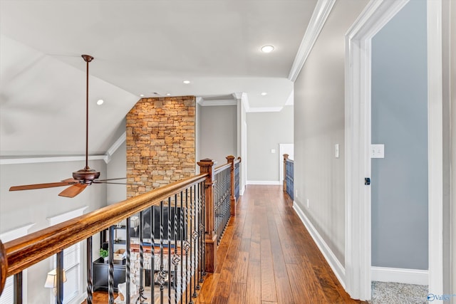 hallway featuring ornamental molding, baseboards, an upstairs landing, and hardwood / wood-style flooring