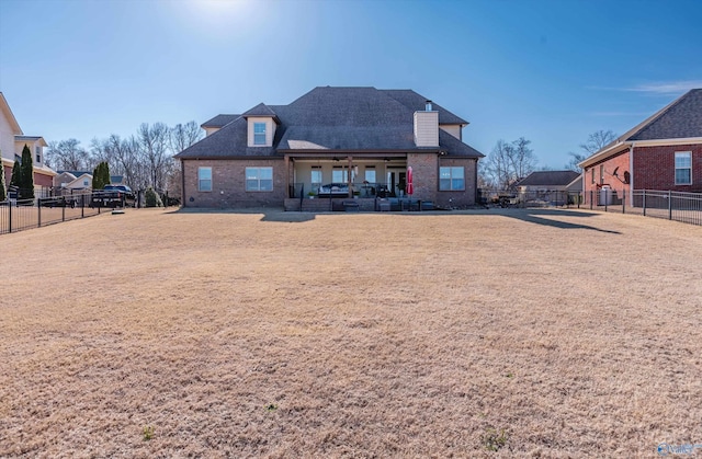 rear view of house with brick siding, a patio area, and a fenced backyard