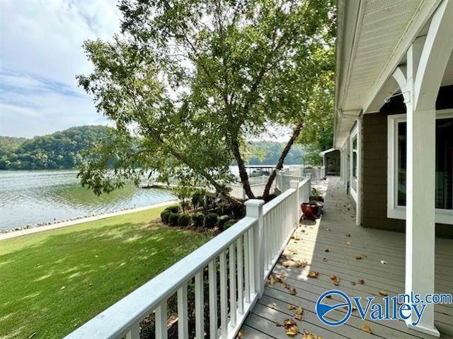 wooden deck with a water view and a lawn