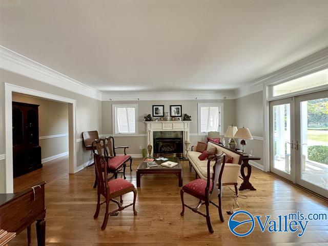 living room with french doors, a fireplace, wood finished floors, and crown molding