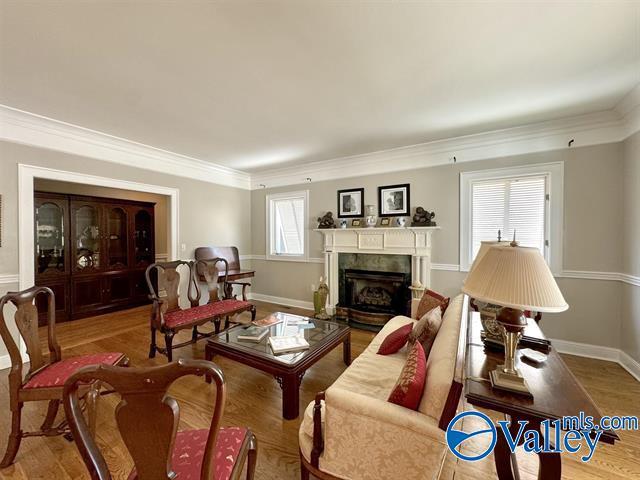 living area featuring a fireplace, baseboards, wood finished floors, and ornamental molding