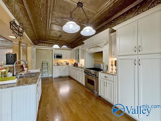 kitchen with dark wood-style flooring, a sink, white cabinetry, appliances with stainless steel finishes, and an ornate ceiling