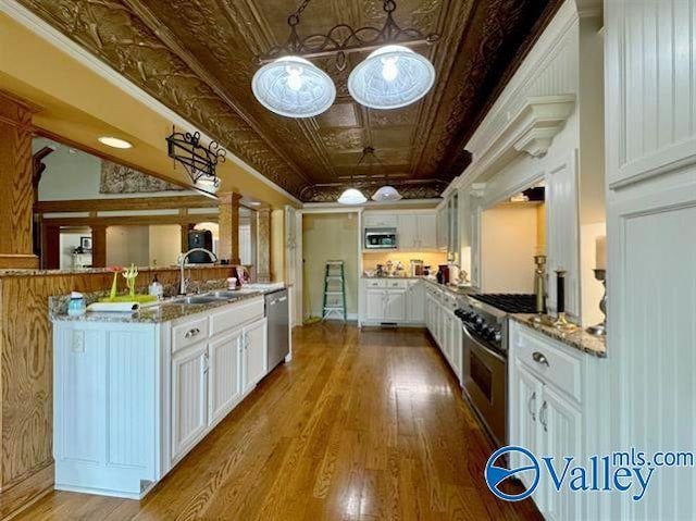 kitchen with stainless steel appliances, a sink, an ornate ceiling, and white cabinets