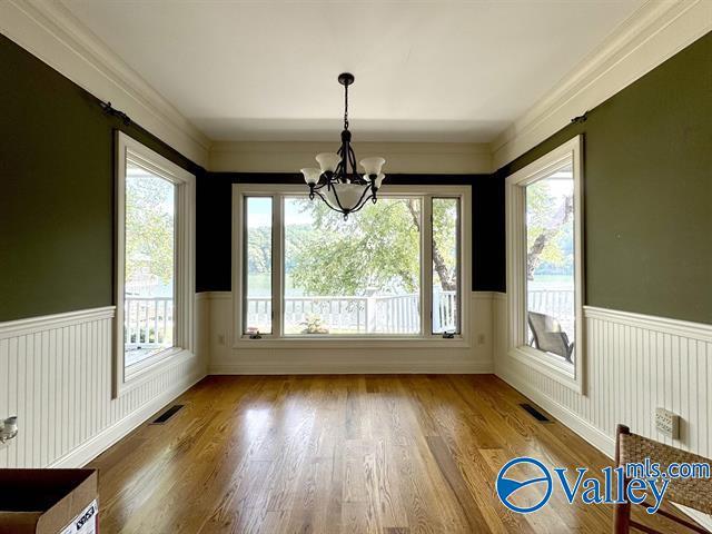 unfurnished dining area with visible vents, wood finished floors, and wainscoting