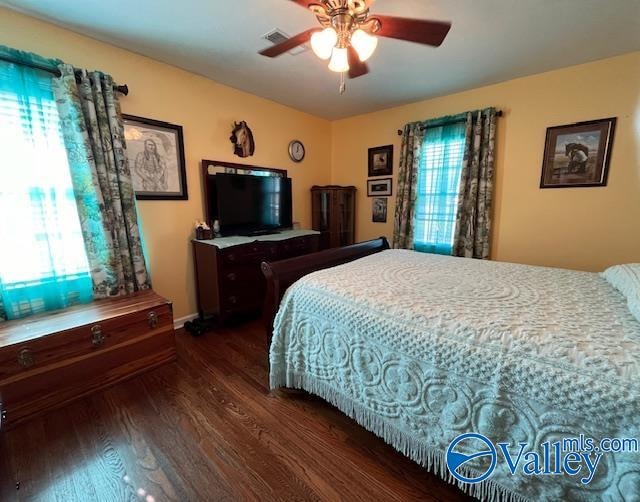 bedroom with multiple windows, ceiling fan, and dark wood-type flooring