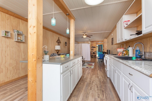 kitchen featuring ceiling fan, pendant lighting, sink, wood walls, and light hardwood / wood-style flooring