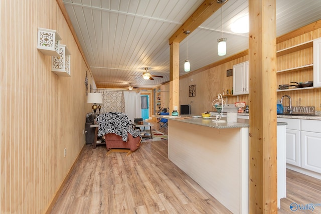 kitchen featuring white cabinets, light hardwood / wood-style flooring, wooden walls, and ceiling fan