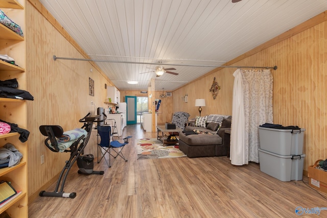 workout room featuring light hardwood / wood-style flooring, ceiling fan, and wooden walls