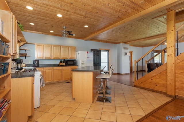 kitchen with light wood-type flooring, white appliances, a center island, beam ceiling, and a kitchen breakfast bar