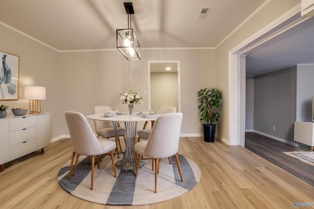 dining room featuring crown molding and light hardwood / wood-style floors