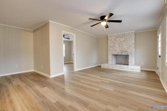 unfurnished living room featuring ceiling fan, a brick fireplace, light hardwood / wood-style flooring, a healthy amount of sunlight, and ornamental molding