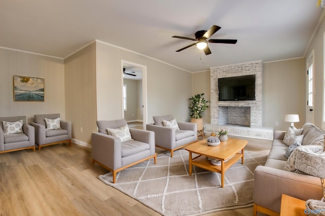 living room with a brick fireplace, light hardwood / wood-style flooring, ornamental molding, and ceiling fan