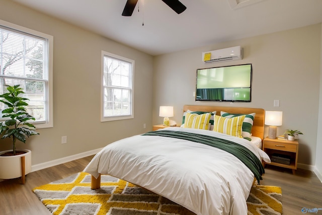 bedroom with ceiling fan, hardwood / wood-style flooring, an AC wall unit, and multiple windows