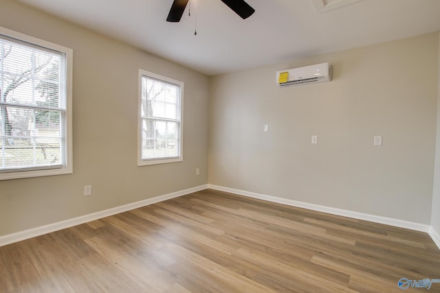 unfurnished room featuring ceiling fan, a wealth of natural light, light hardwood / wood-style flooring, and a wall unit AC