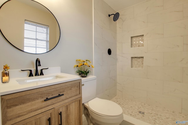 bathroom featuring toilet, vanity, and tiled shower