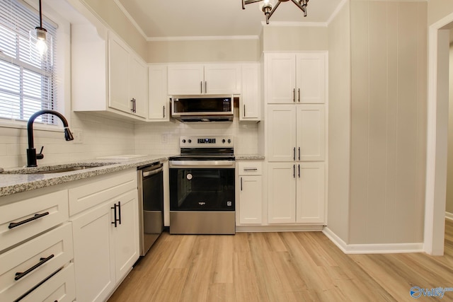 kitchen featuring appliances with stainless steel finishes, white cabinetry, sink, backsplash, and light hardwood / wood-style flooring