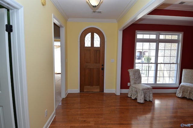 foyer featuring wood finished floors, a healthy amount of sunlight, visible vents, and ornamental molding