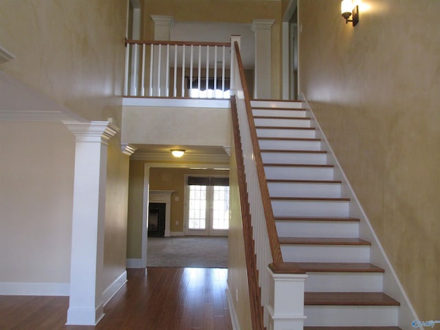 stairway featuring hardwood / wood-style flooring, crown molding, and ornate columns