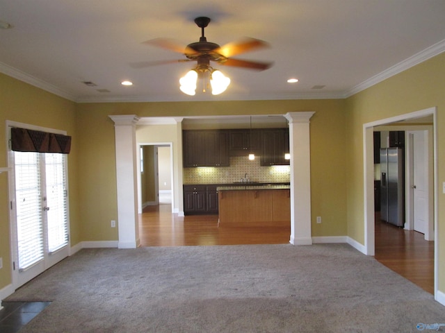 unfurnished living room with ceiling fan, ornamental molding, carpet, and ornate columns