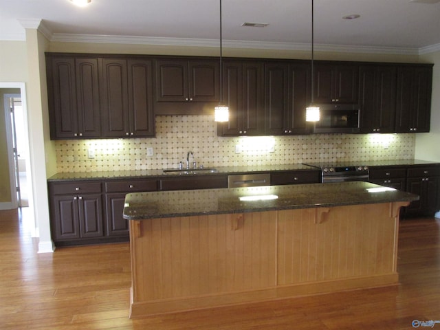 kitchen with a center island, decorative light fixtures, stainless steel appliances, sink, and light wood-type flooring