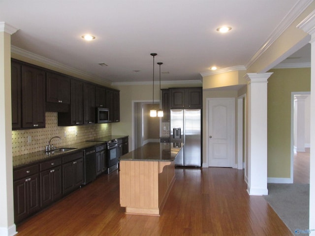 kitchen with ornate columns, hanging light fixtures, sink, a kitchen island, and stainless steel appliances